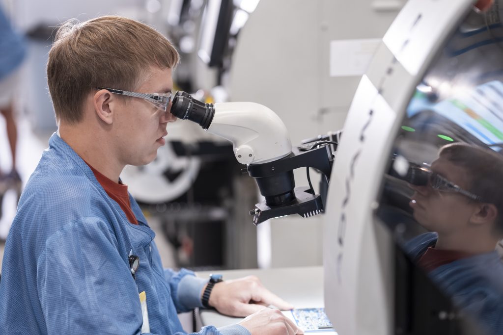 Technician using a microscope in an aerospace research laboratory.